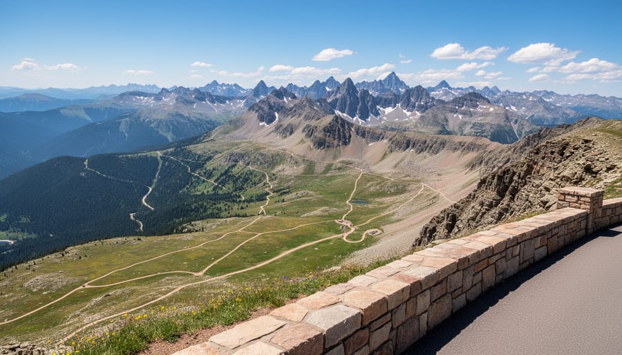 A hiker stands at a Rocky Mountain National Park overlook with alpine lakes and snow-dusted peaks in the distance.
